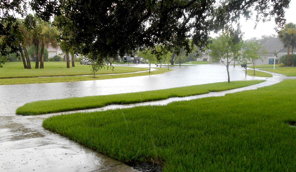 Storm drain and swale carrying heavy rain runoff on a commercial landscape